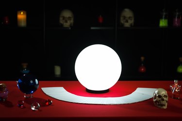 Luminous crystal ball and cards on magnificent fortune telling table.