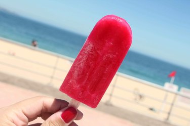 Hand holding popsicle at beach