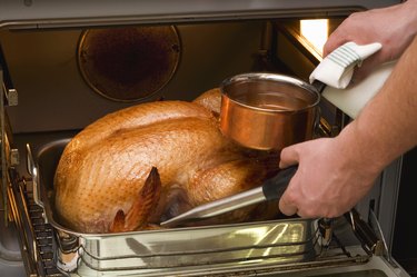 Basting turkey with roasting juices, in the oven