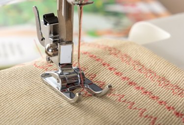 Sewing machine foot with a needle sews fabric. Close-up. Place for text