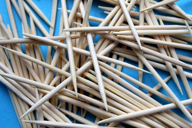 A pile of wooden toothpicks lie on a blue background.
