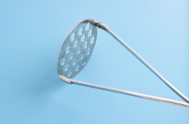 Potato masher against a blue background