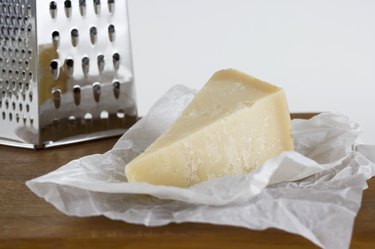 Parmesan cheese and grater on wooden cutting board