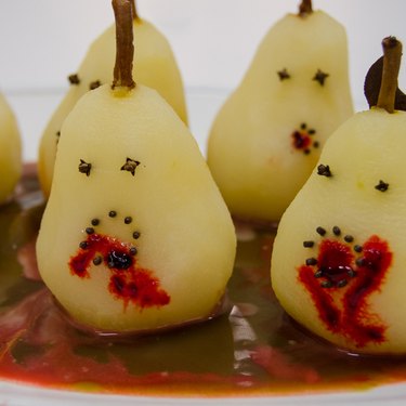 Poached pears with faces made of cloves