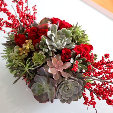 ...A centerpiece featuring succulents, but also using roses, greenery and other decorative elements.