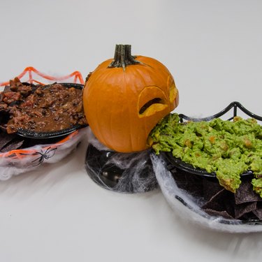 Small pumpkin with guacamole on one side and salsa on the other