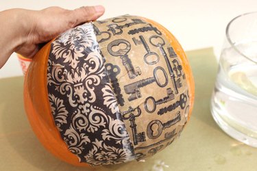 Overlap the paper sections to fully cover the pumpkin