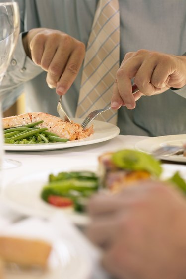 Businessman eating at restaurant table, mid section