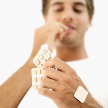 Low angle view of a young man eating nicotine gum from a strip