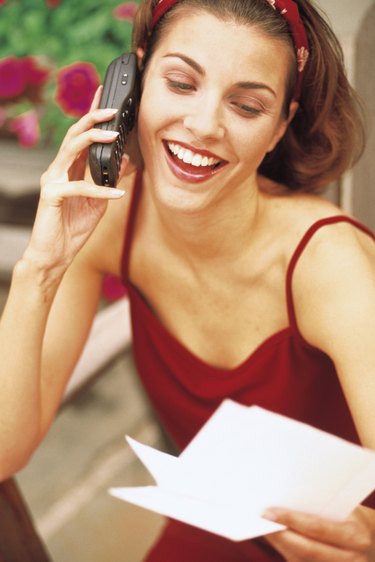 Woman talking on cell phone and holding letter or note