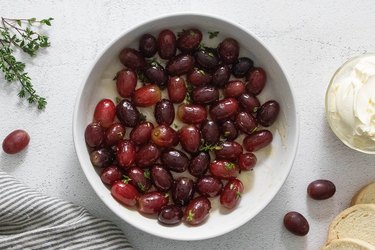 Red grapes with olive oil, honey, salt and thyme in a white bowl