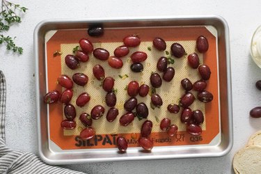 Red grapes on a baking sheet lined with a silicone mat