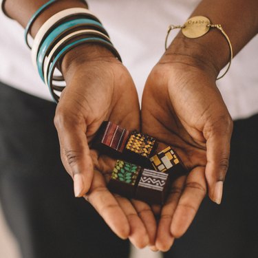 Five colorfully painted Ghanaian chocolates in a woman's hands