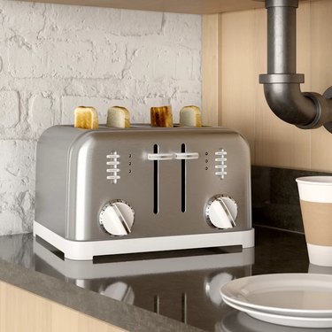 Silver Cuisinart toaster with four slices of toast on dark countertop.