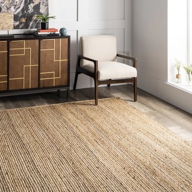 Large natural jute fiber rug on medium-tone hardwood floor in living room.
