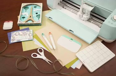 A mint colored Cricut machine with supplies and paper