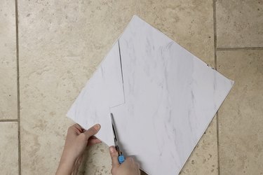 Cutting a vinyl floor tile with scissors