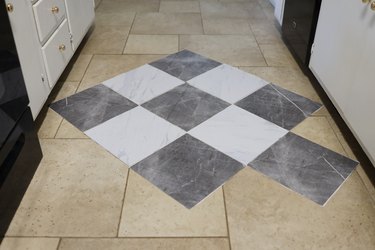 Faux marble vinyl floor tiles laid out on top of tile floor