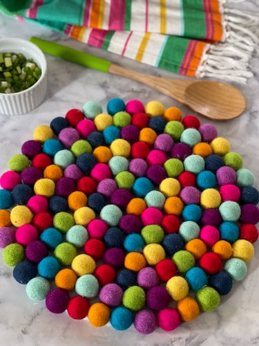 pompom place mat styled with spoon, towel and small bowl
