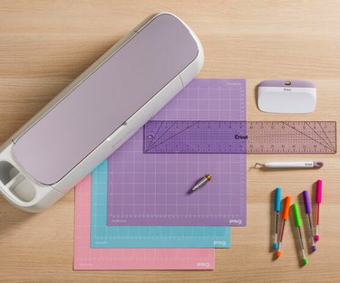 A purple Cricut machine with cutting mats and tools