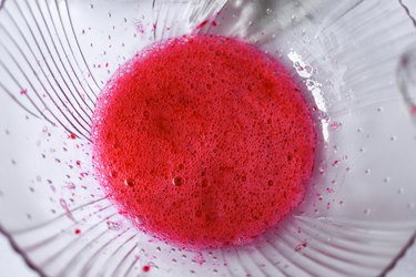 Bowl of frothy egg whites with pink gel food coloring