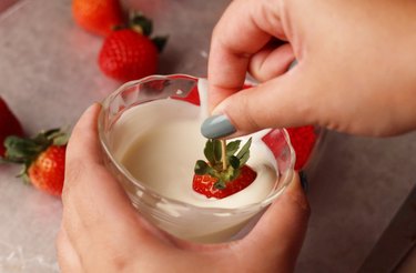 Dipping strawberry in melted white chocolate.