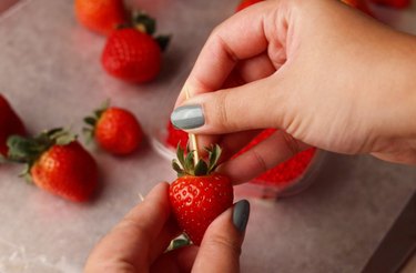 Skewering a strawberry with a toothpick.
