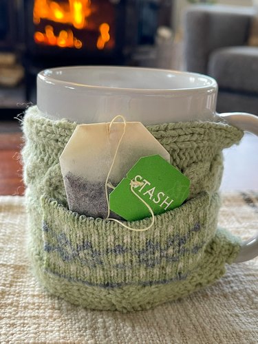 finished mug cozy with tea bag in pocket by fireplace