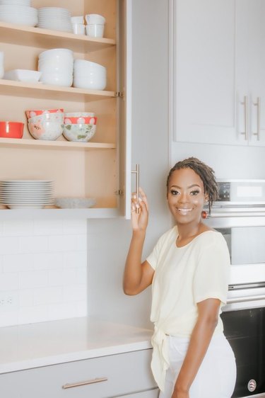 Kenika Williams stands in front of decluttered kitchen cabinets