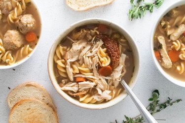 Three types of chicken noodle soup in bowls