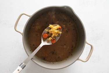 Adding pasta to soup in a large pot