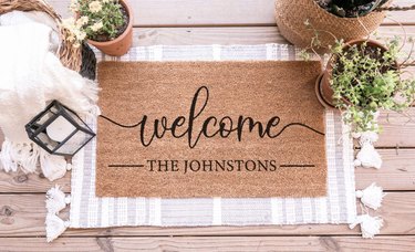 Custom coir doormat that reads, "Welcome" in handwriting script, and then ——The Johnstons—— underneath in an all-caps straighter font.