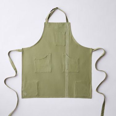 Green apron from Food52 with multiple pockets, a string-tie back, and an adjustable neck strap.
