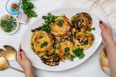 Charred cabbage steaks with chimichurri served on a white platter.