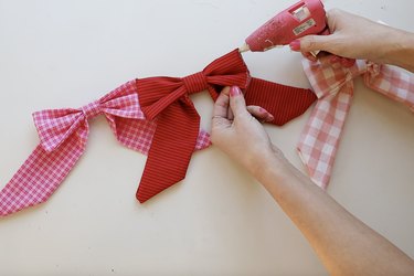 Gluing red and pink fabric bows together to form a garland