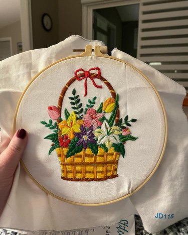 An embroidery hoop showing a basket filled with colorful flowers