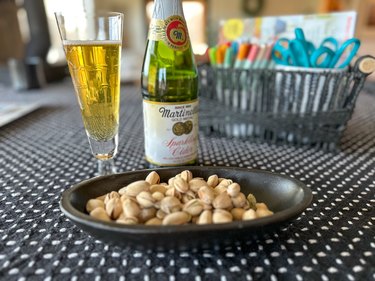 Sparkling cider and pistachios on a table with basket full of vision board supplies