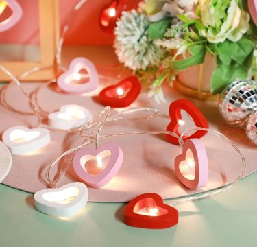 LED wood heart lights on a table surrounded by mini disco balls and flowers.