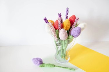 A bouquet of crocheted flowers in a clear glass vase.