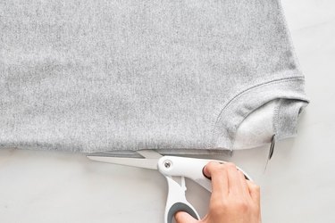 Cutting top layer of gray sweatshirt
