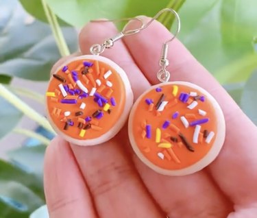 Orange sugar cookie earrings with purple, yellow, brown, orange and white sprinkles