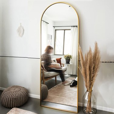 Gold finished full length mirror with an arched top.