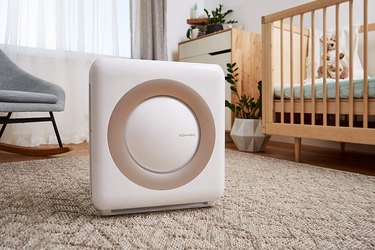 White air purifier with a rose gold colored circle on the front in a baby's nursery.
