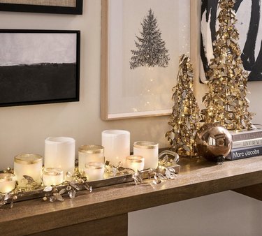 Two Christmas tree decorations on shelf next to candles