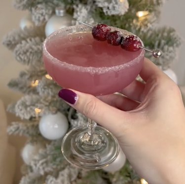 Reddish cocktail in glass with cranberry garnish