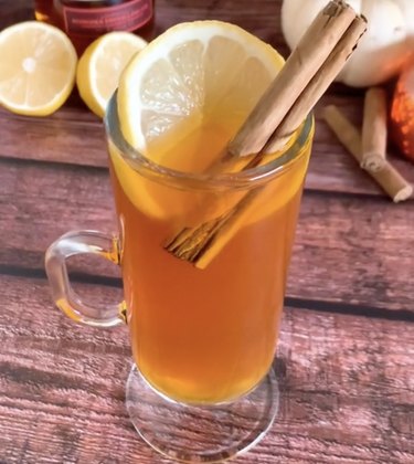 Fall-themed hot toddy drink in a glass with a cinnamon stick and lemon slice