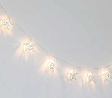 Star string lights hanging on white wall.