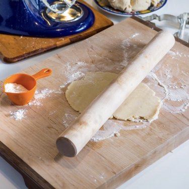 J.K. Adams maple dowel-style rolling pin shown on a wooden pastry board rolling out dough.