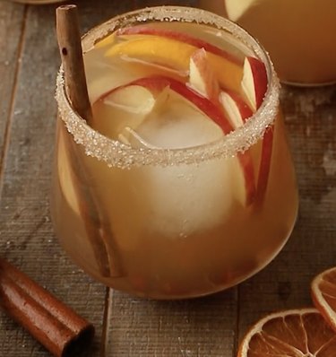 Light sangria in a glass with apple slices and a cinnamon stick