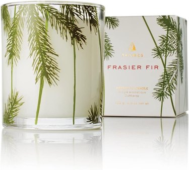 Thymes Pine Needle Frasier Fir Candle in a clear glass vessel with pine sprig motifs on it.